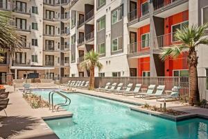 凤凰城Locale Midtown Phoenix的一座带椅子和棕榈树的室外游泳池,位于一座大楼内