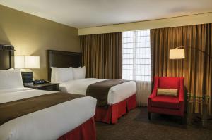 洛杉矶洛杉矶市中心希尔顿逸林酒店的酒店客房,设有两张床和一张红色椅子