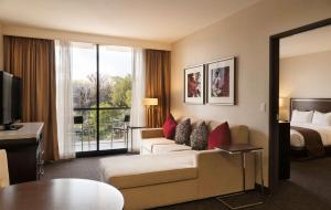 洛杉矶洛杉矶市中心希尔顿逸林酒店的酒店客房设有沙发、床和电视。