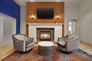 新奥尔良新奥尔良会展中心希尔顿花园酒店的客厅配有两把椅子和壁炉