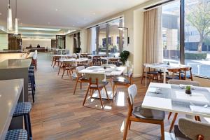 帕萨迪纳帕萨迪纳希尔顿酒店的餐厅设有桌椅和窗户。