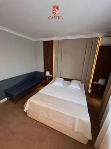 拉姆尼库沃尔恰卡斯特利酒店的卧室配有白色的床和蓝色的沙发
