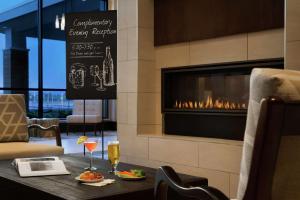 锡拉丘兹Embassy Suites By Hilton Syracuse Destiny USA的餐厅设有壁炉,餐桌上供应食品和饮料