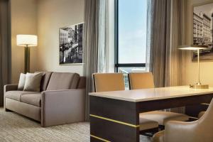 锡拉丘兹Embassy Suites By Hilton Syracuse Destiny USA的客厅配有沙发和书桌。