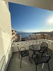 萨兰达Villa Idrizi的阳台配有桌椅,享有海景。
