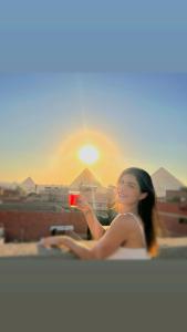 开罗mesho falcon Pyramids view inn的一位拍摄日落景象的女人