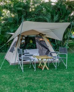 ShiriShose Campsite的草原上带椅子和桌子的帐篷