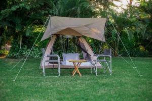 ShiriShose Campsite的草顶帐篷,配有两把椅子和一张桌子