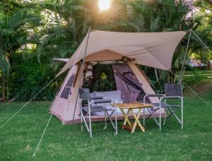 ShiriShose Campsite的草原上带椅子和桌子的帐篷