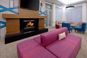 阿尔伯克基阿尔伯克基机场希尔顿花园酒店的客厅配有粉红色的沙发和壁炉