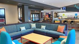 巴尔的摩Tru By Hilton Baltimore Harbor East的一张蓝色沙发,位于一个配有桌子的等候室