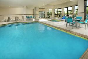 大学城希尔顿花园酒店学院站 的一个带蓝色桌椅的大型游泳池