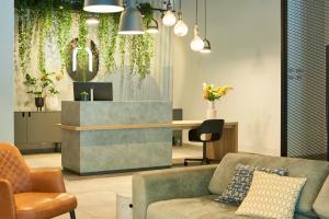 波鸿Nena Apartments Bochum City的大堂配有沙发和植物书桌