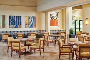 盐湖城盐湖城机场希尔顿逸林酒店的餐厅设有桌椅,墙上挂有绘画作品