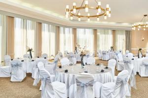 盐湖城盐湖城机场希尔顿逸林酒店的宴会厅配有白色的桌椅和吊灯