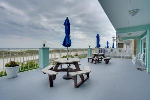 威尔伍德克拉斯特Cozy Oceanfront Condo with Pool and Beach Access!的庭院设有两张野餐桌和一把蓝伞