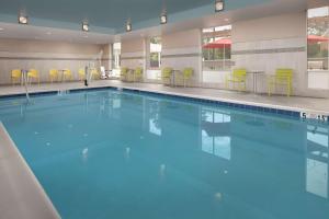 奥因斯米尔斯Home2 Suites By Hilton Owings Mills, Md的一个蓝色的海水和黄色椅子的大型游泳池