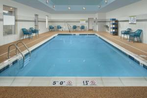 夏洛茨维尔Home2 Suites By Hilton Charlottesville Downtown的周围设有蓝色椅子的大型游泳池