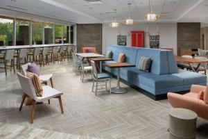 夏洛茨维尔Home2 Suites By Hilton Charlottesville Downtown的大堂设有蓝色的沙发和桌椅