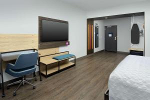 丹佛Tru By Hilton Denver Airport Tower Road的酒店客房设有一张床、一张书桌和一台电视机。
