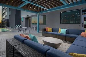 拉伯克Tru By Hilton Lubbock Southwest的一间带蓝色沙发和游泳池的客厅