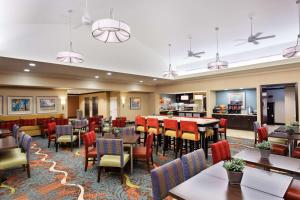 奥兰多奥兰多机场希尔顿惠庭套房酒店的一间带桌椅的餐厅和一间酒吧