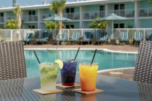 马拉松Hampton Inn Marathon - Florida Keys的坐在泳池旁的桌子上,三杯鸡尾酒