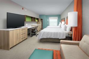 阿什维尔Home2 Suites By Hilton Asheville Biltmore Village的酒店客房配有一张床和一张书桌及一台电视