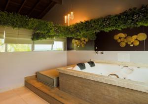 马利西亚斯Amora Hotel Maresias的大型浴室设有壁挂葡萄藤的浴缸。