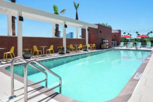 奥兰多Home2 Suites By Hilton Orlando Near Universal的一个带黄色椅子和桌子的大型游泳池