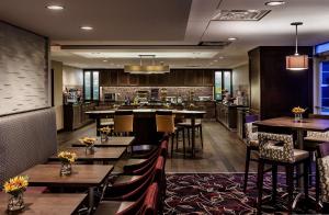 奇克托瓦加布法罗机场希尔顿惠庭套房酒店的一间带桌椅的餐厅和一间酒吧