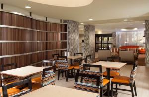 奥兰多Hampton Inn Orlando-International Airport的餐厅拥有木墙和桌椅