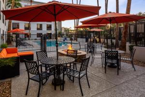 凤凰城凤凰城汉普顿酒店 - 比尔特莫尔的一个带桌椅和红伞的庭院
