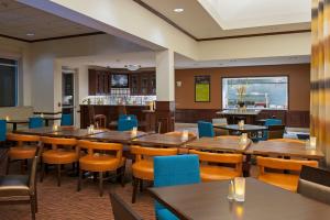 奥克代尔Hilton Garden Inn St. Paul Oakdale的一间带木桌椅的餐厅和一间酒吧