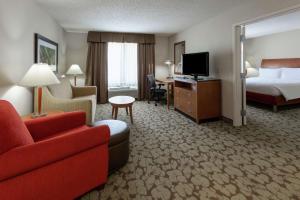奥克代尔Hilton Garden Inn St. Paul Oakdale的酒店客房配有床、沙发和电视。