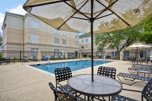 圆石城Hilton Garden Inn Austin Round Rock的游泳池旁配有桌椅和遮阳伞