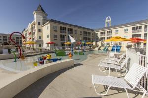 桑达斯基杉树角热浪酒店的一个带椅子和遮阳伞的游泳池和一个游乐场