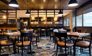 泽西市泽西市希尔顿双树套房酒店的一间带桌椅的餐厅和一间酒吧