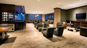 泽西市泽西市希尔顿双树套房酒店的酒店大堂设有椅子、酒吧和电视