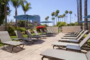 圣地亚哥Embassy Suites by Hilton San Diego La Jolla的庭院里摆放着一排躺椅和遮阳伞
