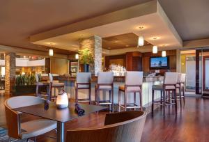 圣地亚哥Embassy Suites by Hilton San Diego La Jolla的餐厅设有酒吧,配有桌椅