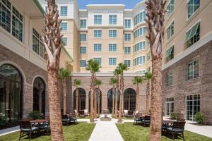 查尔斯顿Embassy Suites by Hilton Charleston Harbor Mt. Pleasant的一座楼前种有棕榈树的庭院