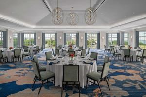 查尔斯顿Embassy Suites by Hilton Charleston Harbor Mt. Pleasant的宴会厅配有桌椅和吊灯。
