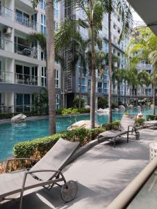 芭堤雅市中心Centara Avenue 2 Bedrooms Pool View的一个带长椅和棕榈树的度假游泳池