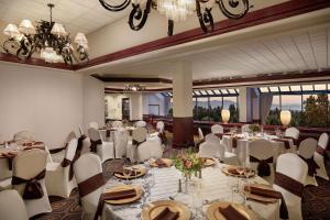 西塔科西雅图机场希尔顿逸林酒店的宴会厅配有白色的桌椅和吊灯。