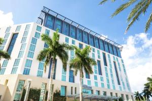 西棕榈滩西棕榈滩希尔顿酒店的一座高大的白色建筑,前面有棕榈树