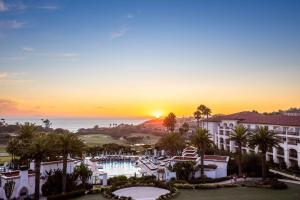 丹纳岬Waldorf Astoria Monarch Beach Resort & Club的日落时分,在拥有游泳池和棕榈树的度假村