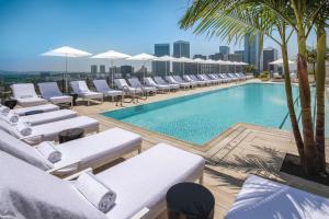 洛杉矶贝弗利山华尔道夫酒店的大楼内带躺椅和遮阳伞的游泳池