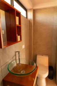 洛维托斯Che Lobitos的一间带玻璃水槽和卫生间的浴室