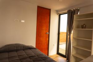 洛维托斯Che Lobitos的一间卧室配有一张床,一扇门设有窗户